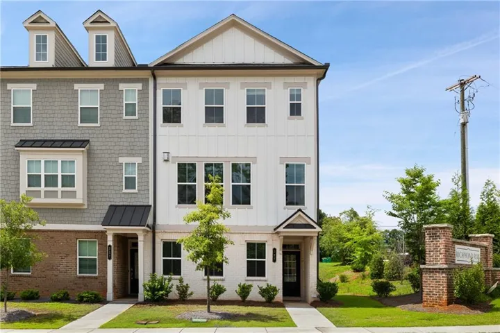 Modern townhome exterior featuring white vertical siding and brick accents