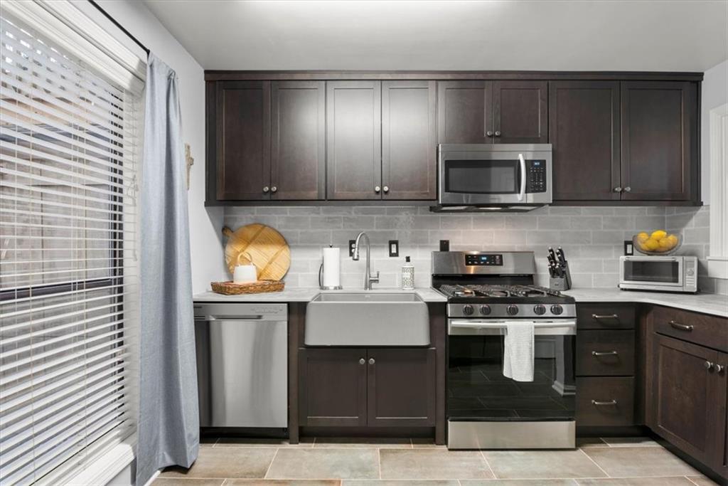 Kitchen with tasteful backsplash, appliances with stainless steel finishes, sink, and dark brown cabinets