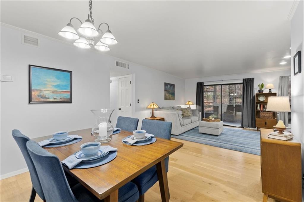 Dining room featuring an inviting chandelier, light hardwood floors, and ornamental molding