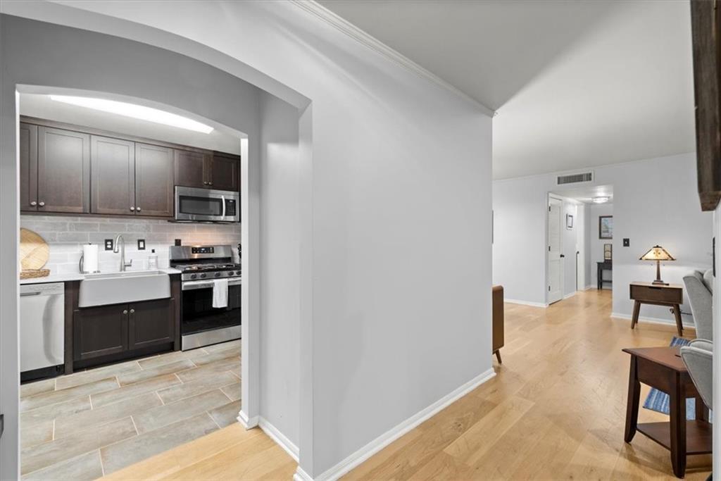 Kitchen with dark brown cabinets, tasteful backsplash, sink, stainless steel appliances, and light tile flooring