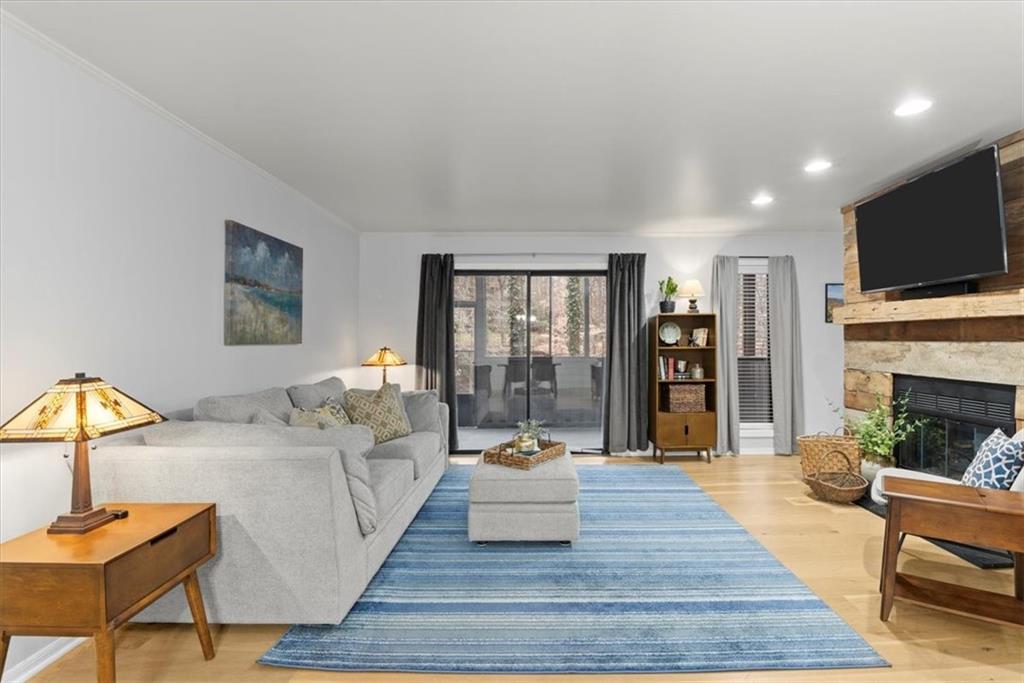 Living room with a fireplace, ornamental molding, and wood flooring