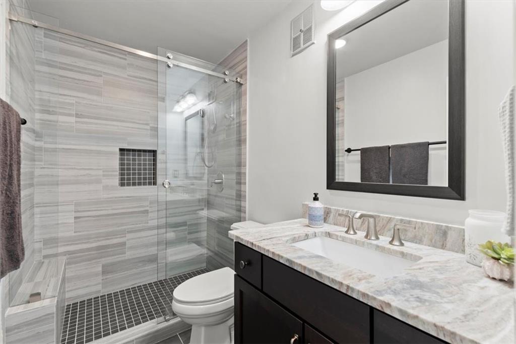 Secondary bathroom with honed granite countertops and walk-in tile shower.
