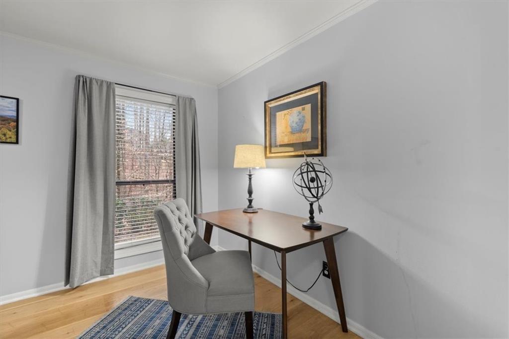 Office with light hardwood / wood-style floors, crown molding, and a healthy amount of sunlight
