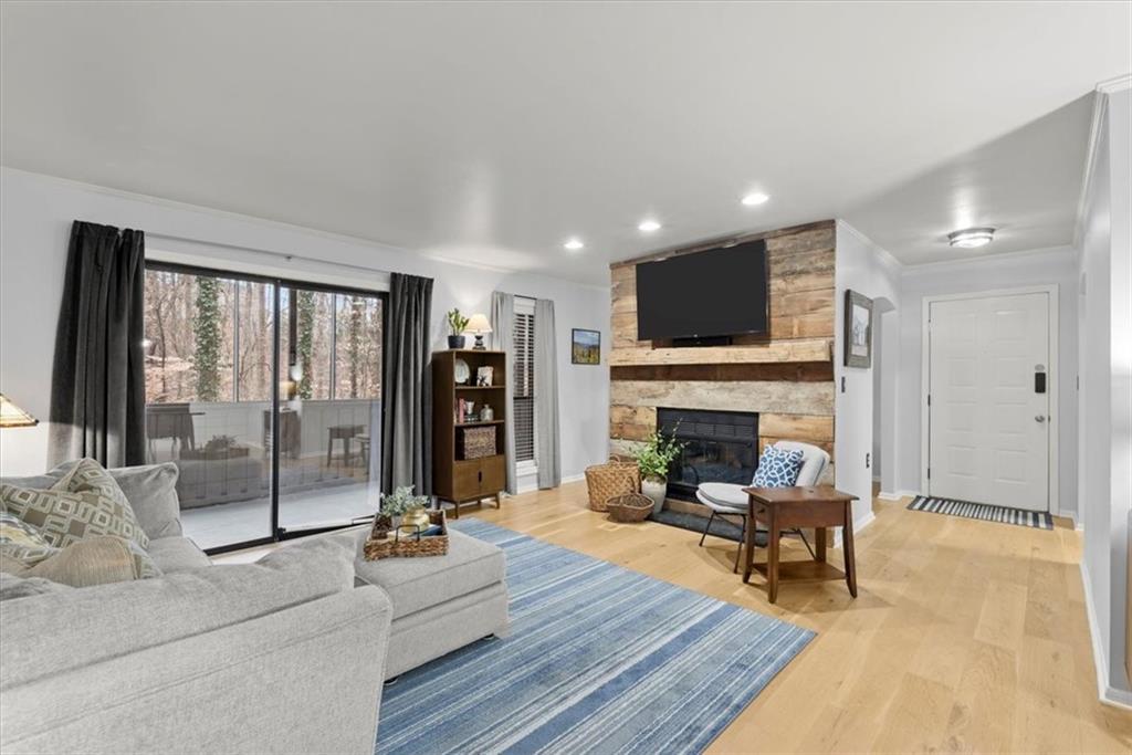 Living room with crown molding, a fireplace, and wood flooring