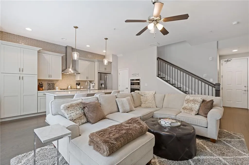 Living room with dark wood finished floors, recessed lighting, a ceiling fan, and stairway