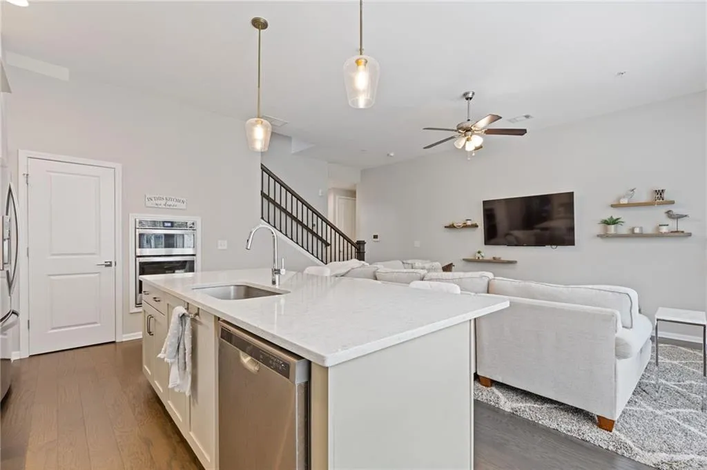 Kitchen featuring pendant lighting, appliances with stainless steel finishes, dark wood finished floors, and light stone counters
