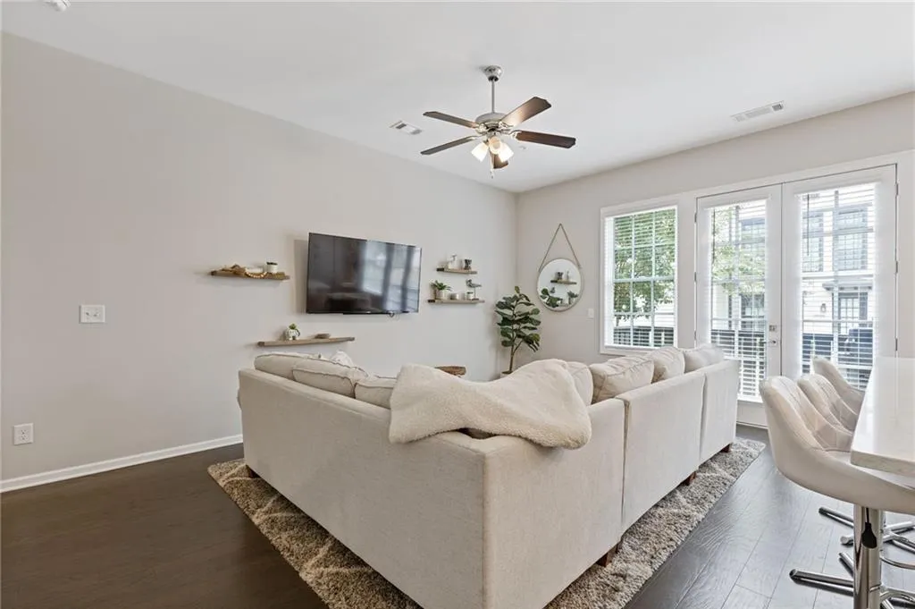 Living room with dark wood finished floors, ceiling fan, and french doors