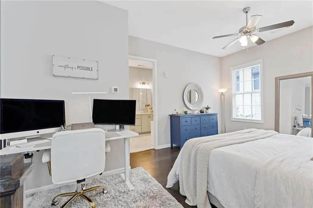 Bedroom featuring a desk, dark wood-style floors, ceiling fan, and connected bathroom