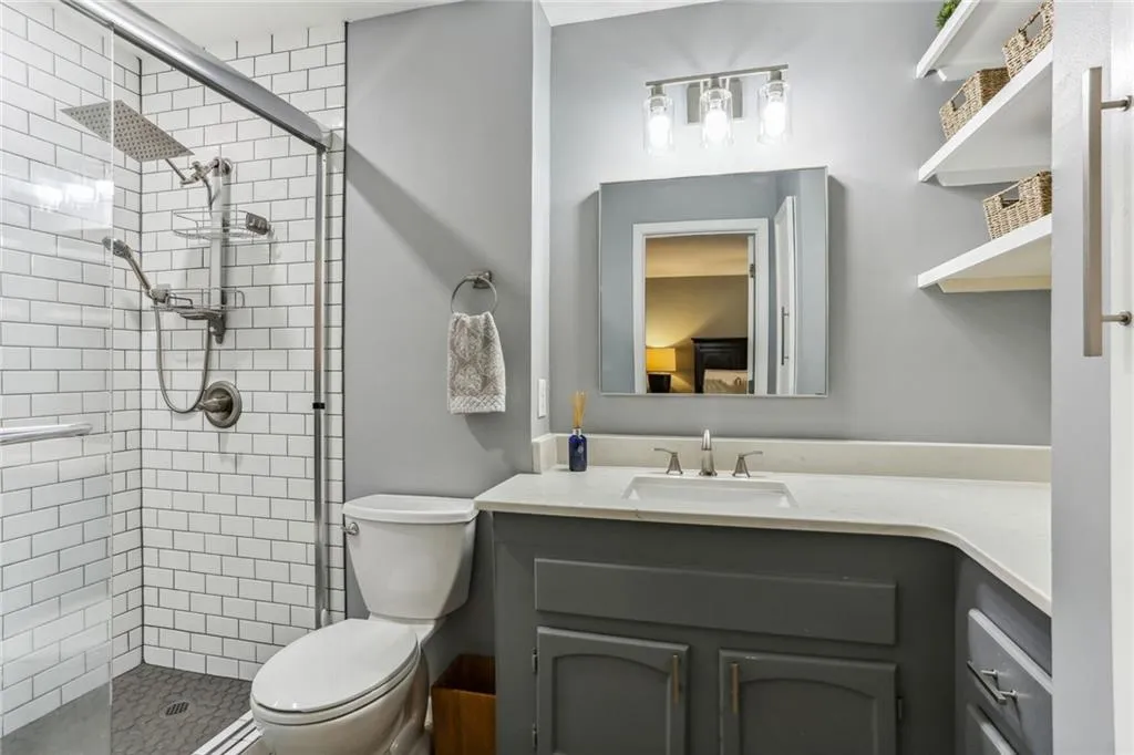 Bathroom featuring an enclosed shower, toilet, and shelves. Bathroom featuring an enclosed shower, toilet, and shelves.