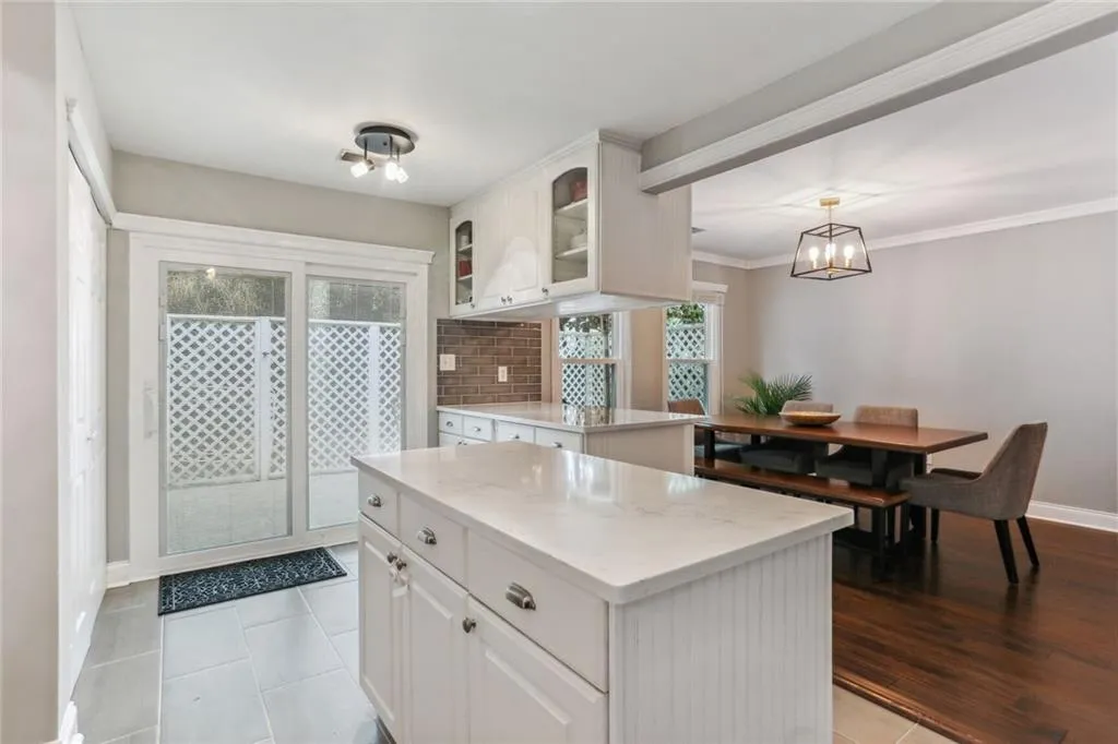 Kitchen with pendant lighting, a kitchen island, tasteful backsplash, white cabinets, and an inviting chandelier Kitchen with pendant lighting, a kitchen island, tasteful backsplash, white cabinets, and an inviting chandelier