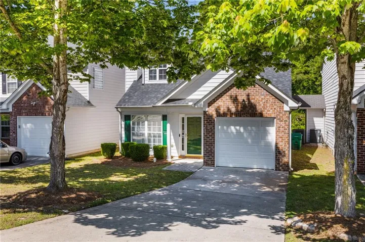 Brick and siding exterior featuring a white garage door, green window shutters, and a front entry with sidelights