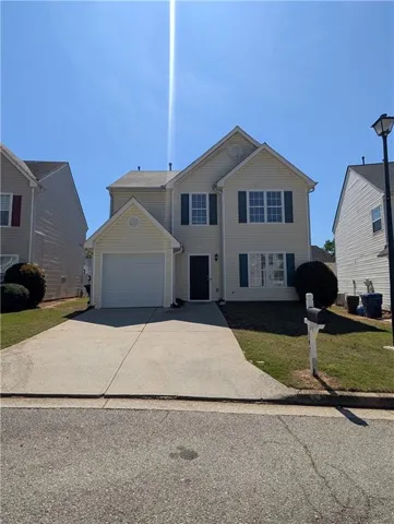 View of front of property with a front lawn, driveway, and a garage