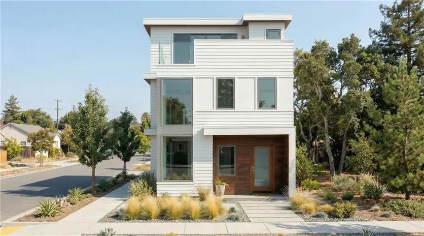 Contemporary exterior with mixed material siding, large format windows, a second-story balcony with a glass railing, and a minimalist landscaping design
