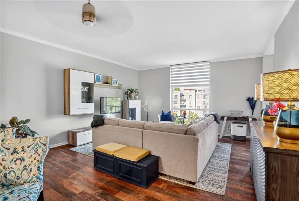 Living room with crown molding, dark wood-type flooring, and a ceiling fan Living room with crown molding, dark wood-type flooring, and a ceiling fan
