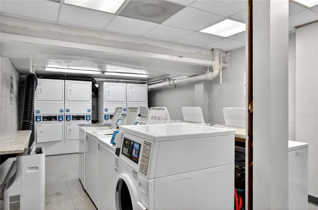 Communal laundry room featuring stacked washer and clothes dryer, a drop ceiling, and washer and dryer Communal laundry room featuring stacked washer and clothes dryer, a drop ceiling, and washer and dryer