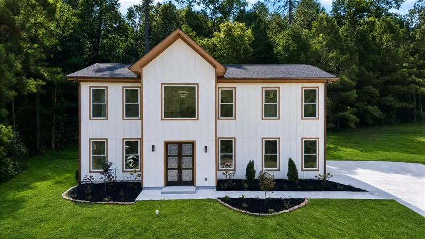 Modern farmhouse exterior featuring white vertical siding and dark brown trim accents