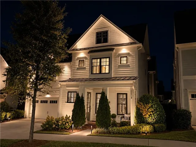 White siding exterior with dark-framed windows, a covered front porch, and an attached two-car garage