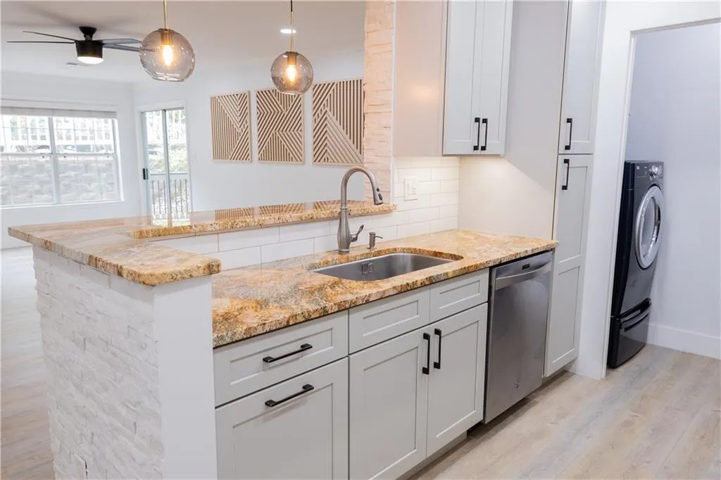 Kitchen featuring decorative light fixtures, backsplash, ceiling fan, sink, and stainless steel dishwasher