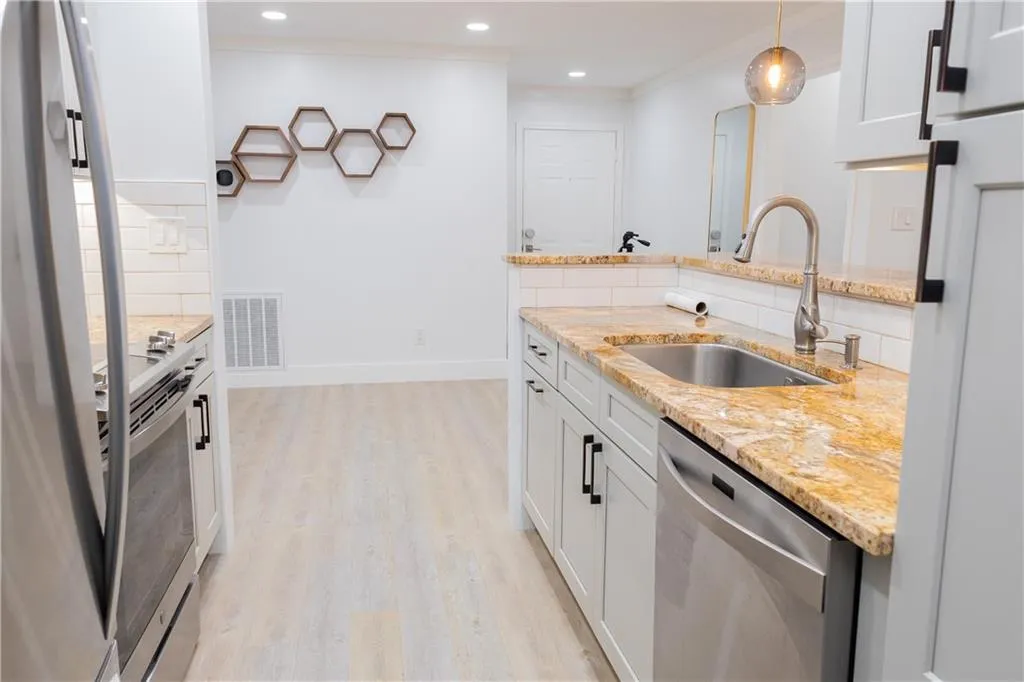 Kitchen with white cabinets, pendant lighting, tasteful backsplash, and light hardwood / wood-style floors