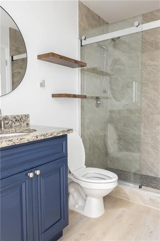 Bathroom with wood-type flooring, toilet, walk in shower, and vanity