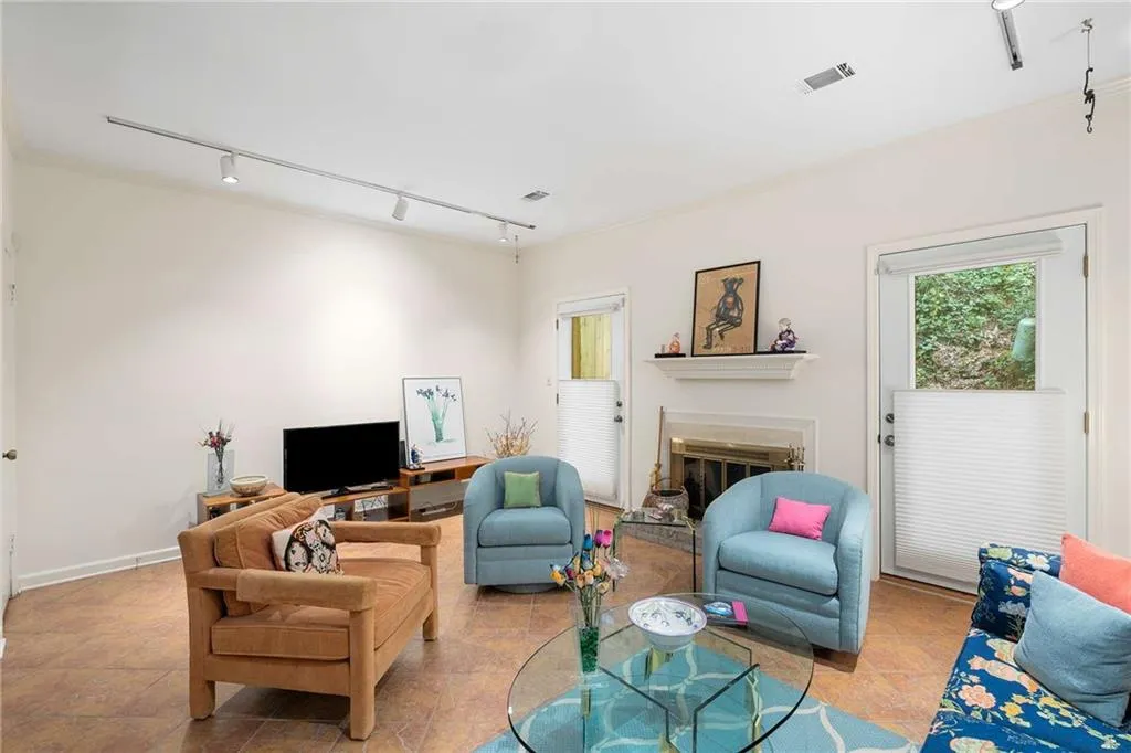 Living room featuring track lighting, a glass covered fireplace, and visible vents