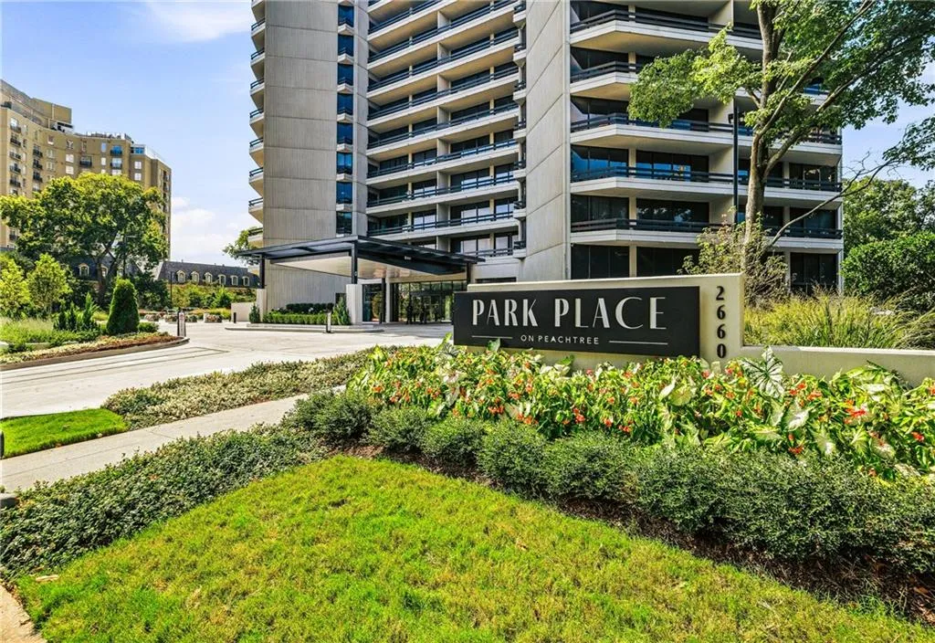 Multi-story building exterior with a covered entrance, contemporary signage, and structured landscaping featuring shrubs and grass