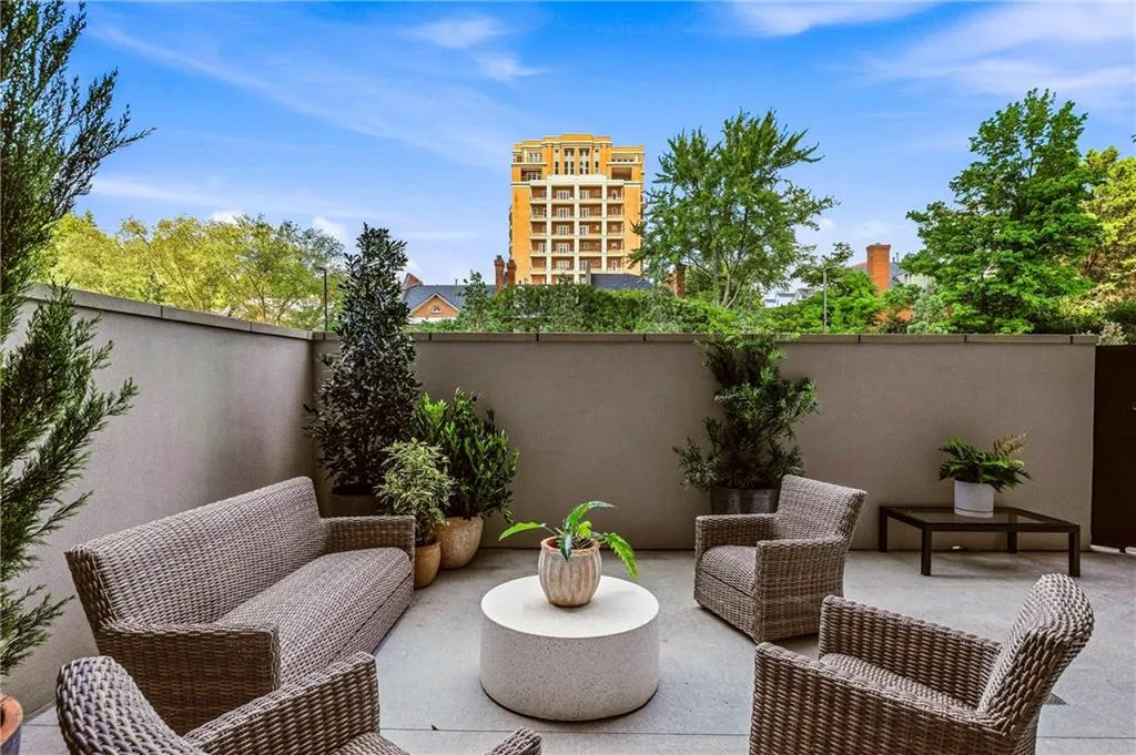 Private outdoor patio space featuring concrete walls, a paved surface, and varied potted plantings