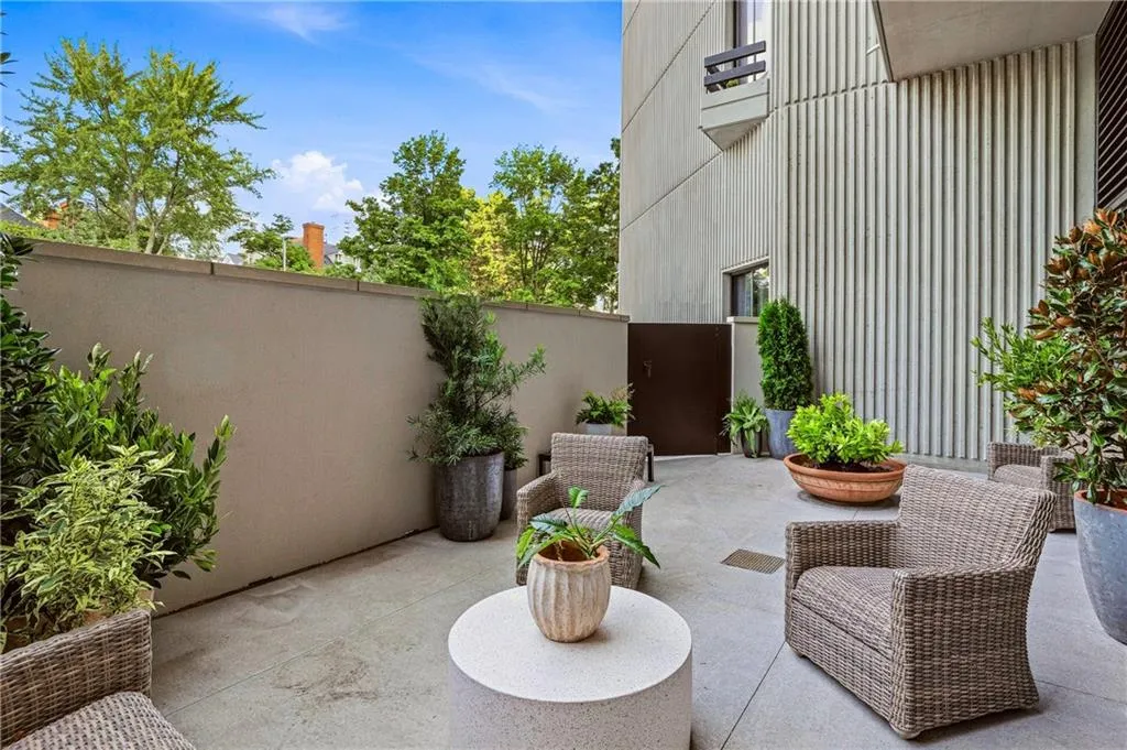 Concrete patio with surrounding privacy wall and a paneled exterior building facade