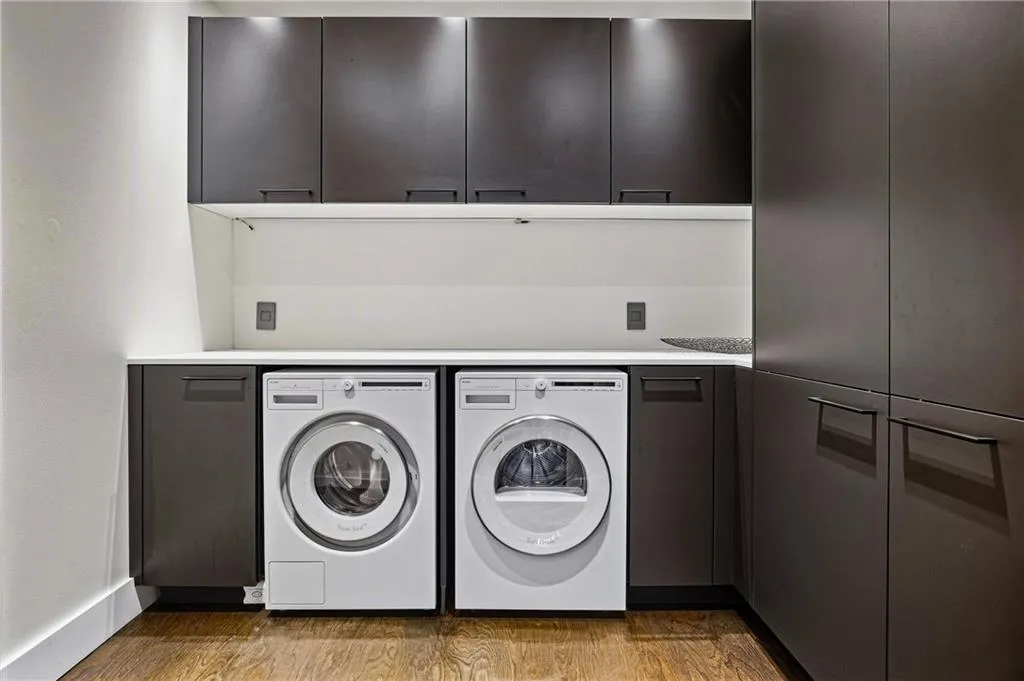 Full-height cabinetry, under-cabinet lighting, integrated washer and dryer, wood-finish flooring, and a white countertop