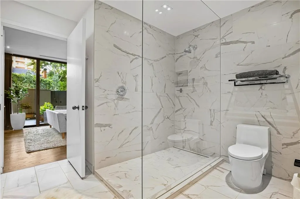 Glass-enclosed shower with full-height tile surround, recessed lighting, and a rainfall showerhead