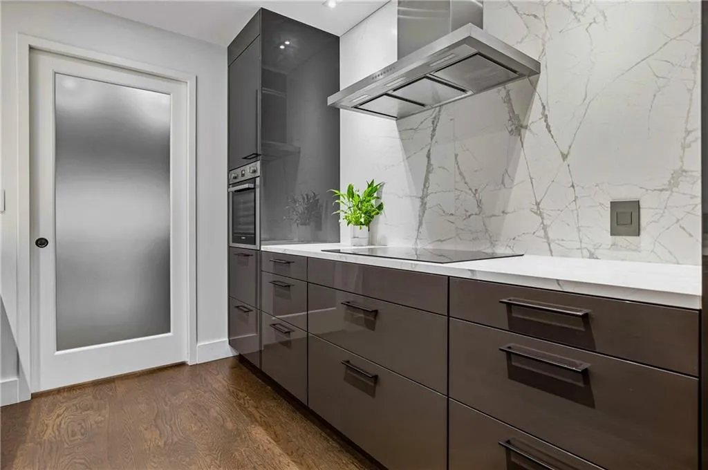 Gleaming wood-finish flooring complements the white countertop and full-height backsplash