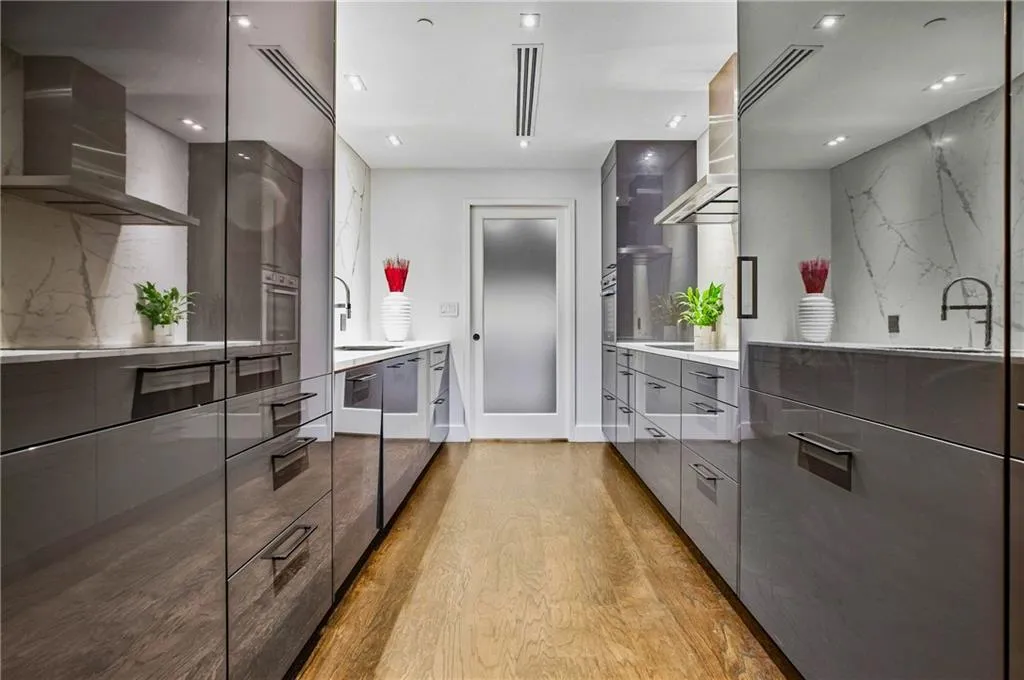 Galley kitchen featuring high-gloss cabinetry, integrated appliances, wood-finish flooring, undermount sink, and recessed lighting