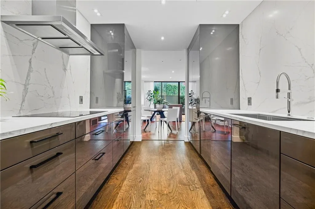 Gourmet kitchen with wood-finish flooring, white countertops, integrated cooktop, stainless steel sink, and a stainless steel range hood