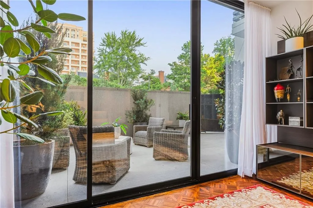 Expansive glass sliding doors open to a private outdoor patio with concrete flooring and perimeter privacy walls