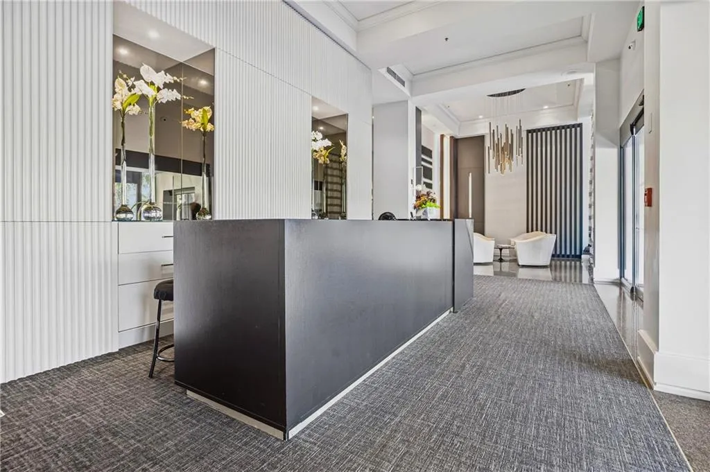 Recessed lighting, decorative wall paneling, built-in cabinetry, elegant chandelier, and textured grey carpet