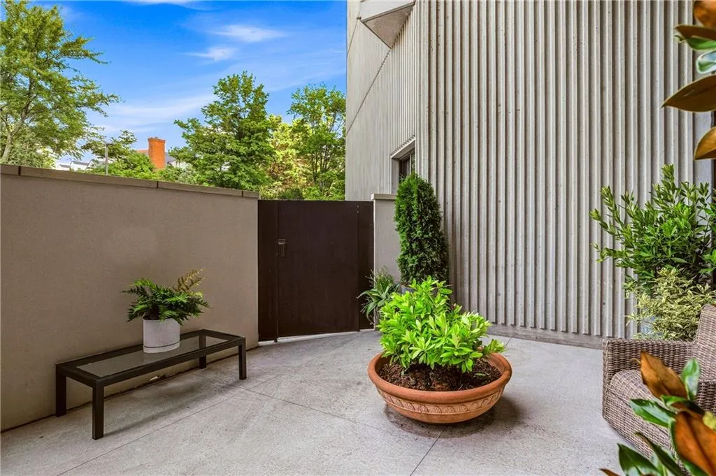 Private outdoor patio with concrete paving, a solid privacy wall, and a dark-toned gate