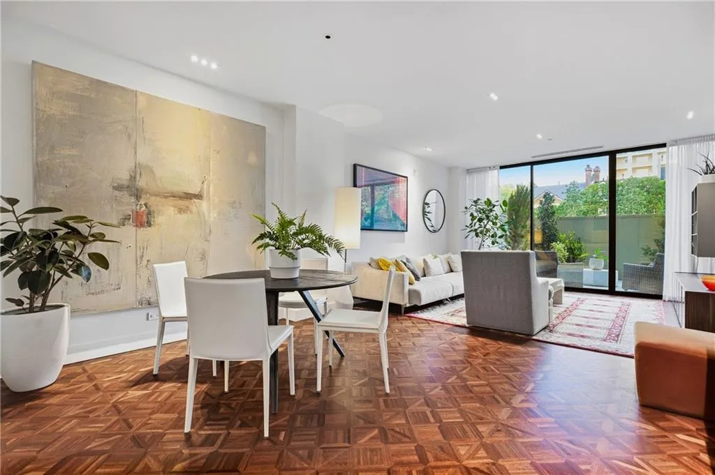 Parquet wood-finish flooring, recessed ceiling lighting, full-height sliding glass panel, and white walls