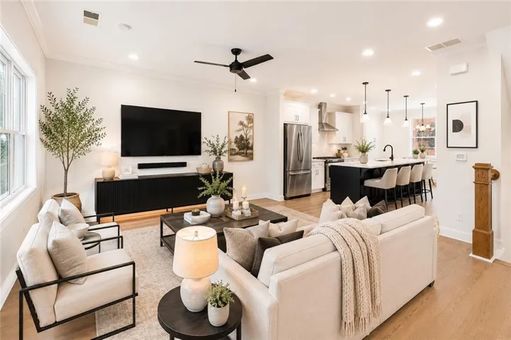 Photo is virtually staged. The family room is filled with natural light from a triple window and a glass door leading to the covered back patio, creating a bright and inviting space to relax or gather.