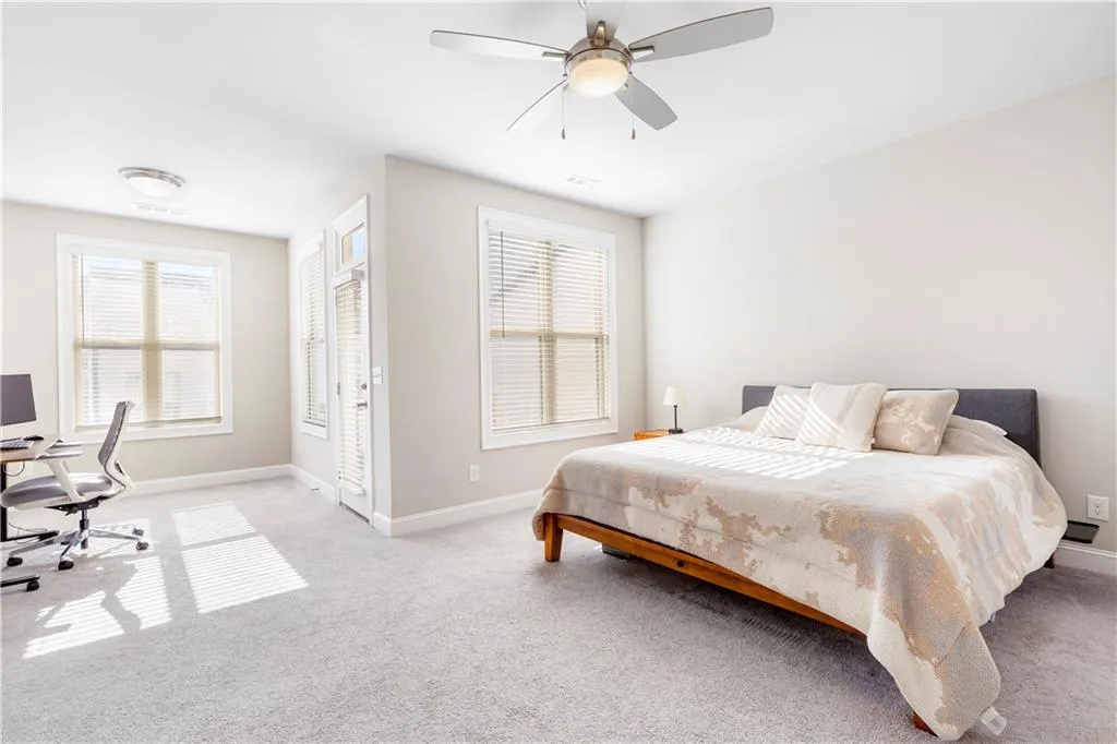 Carpeted bedroom with access to outside, a desk, and ceiling fan