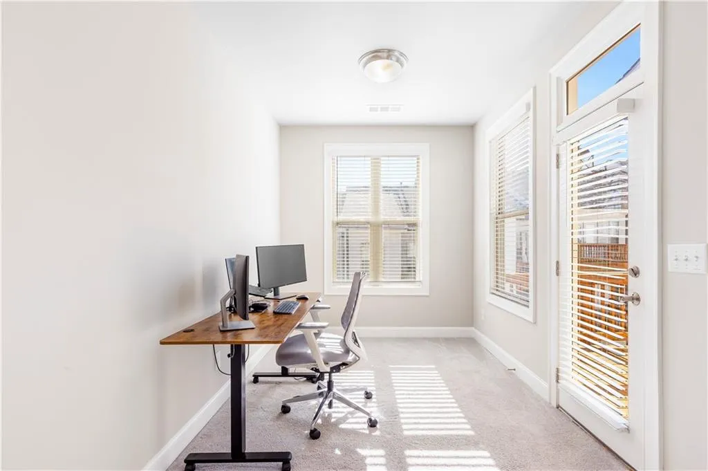 Home office with light carpet and healthy amount of natural light
