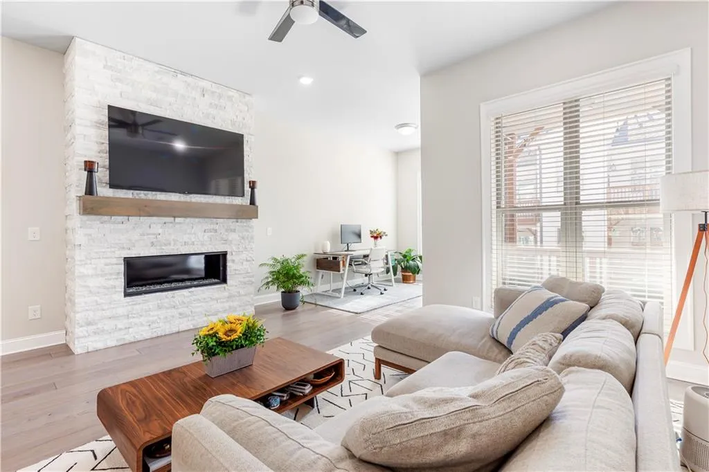 Living area featuring a desk, a fireplace, wood finished floors, and a ceiling fan