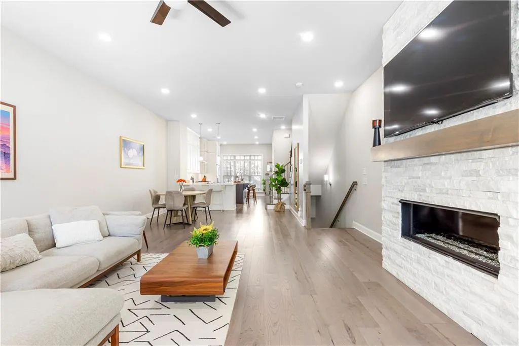 Living room featuring a stone fireplace, light wood-style flooring, recessed lighting, and ceiling fan