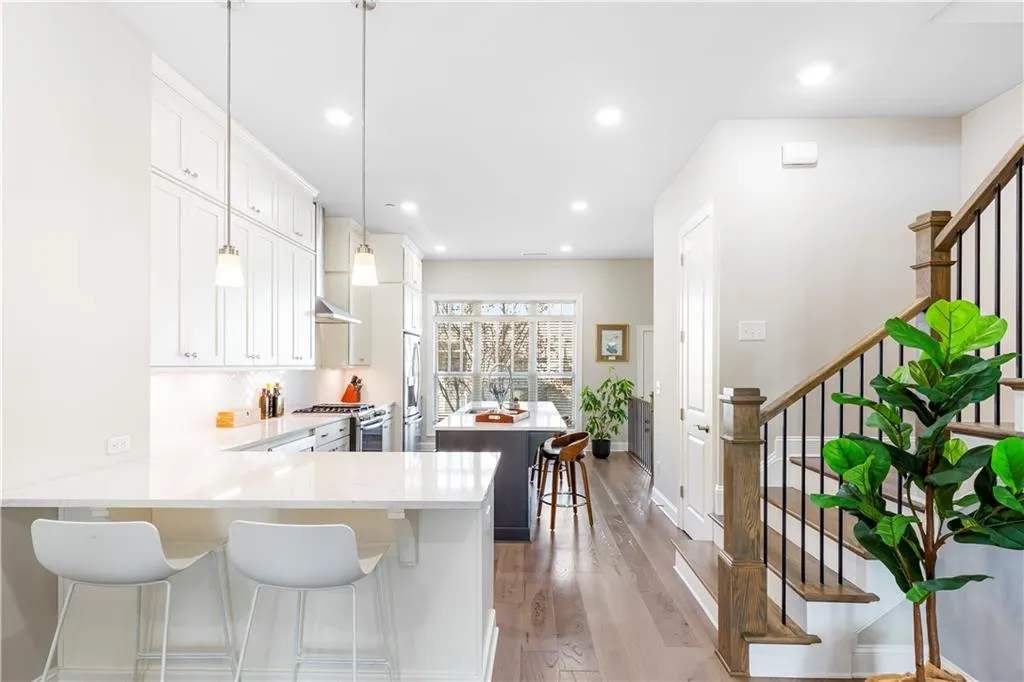 Kitchen featuring a kitchen breakfast bar, a kitchen island, a peninsula, white cabinetry, and stainless steel appliances