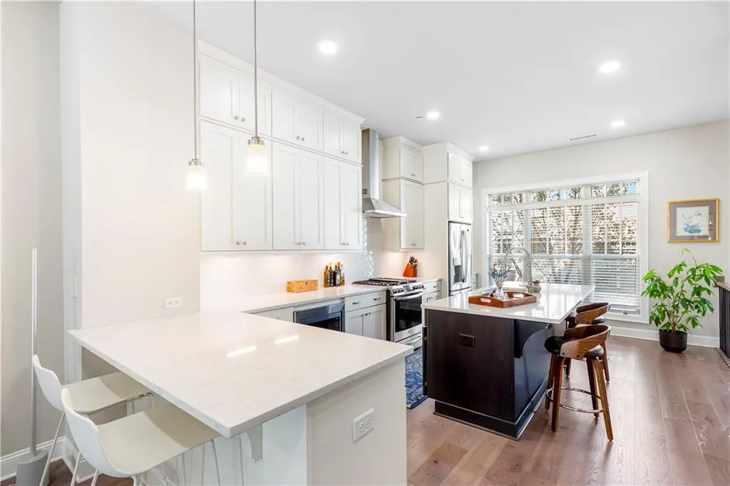Kitchen featuring a kitchen bar, a kitchen island, light wood-style flooring, light stone counters, and white cabinets