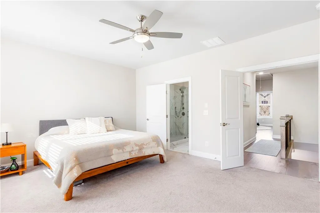 Bedroom featuring attic access, light colored carpet, a ceiling fan, and ensuite bath