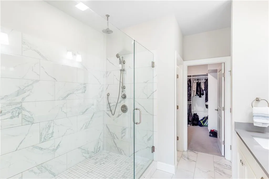 Full bath with vanity, light marble finish flooring, a marble finish shower, and a walk in closet
