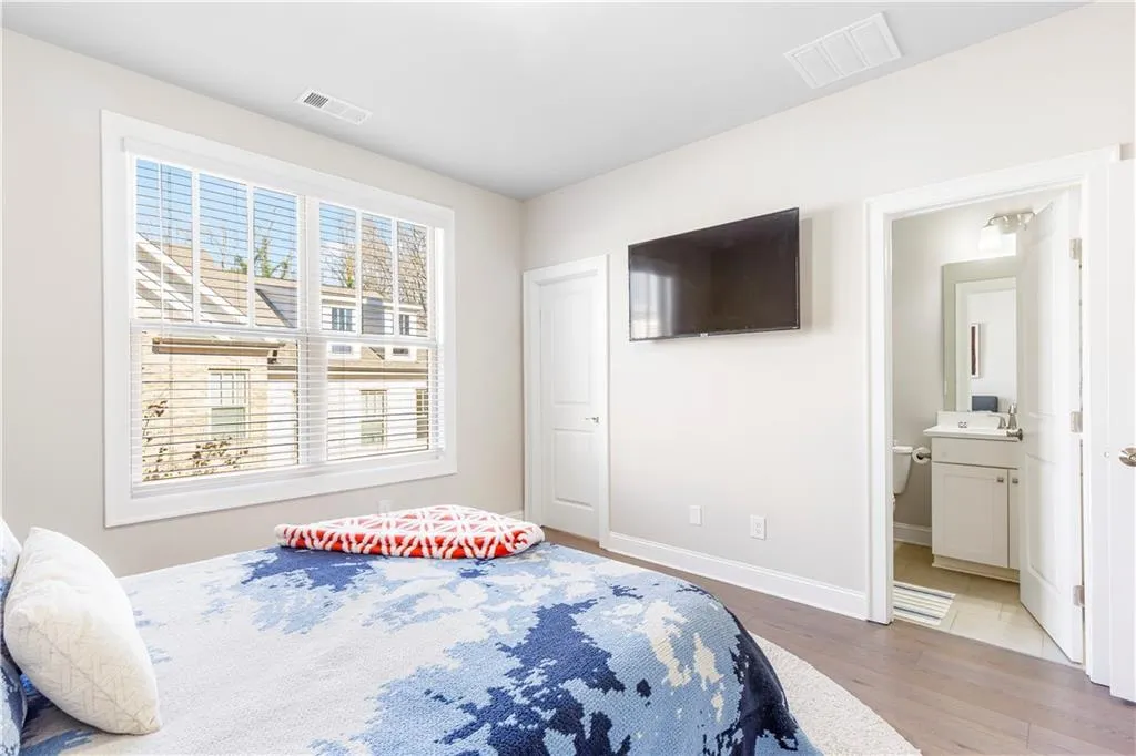 Bedroom with wood finished floors and connected bathroom