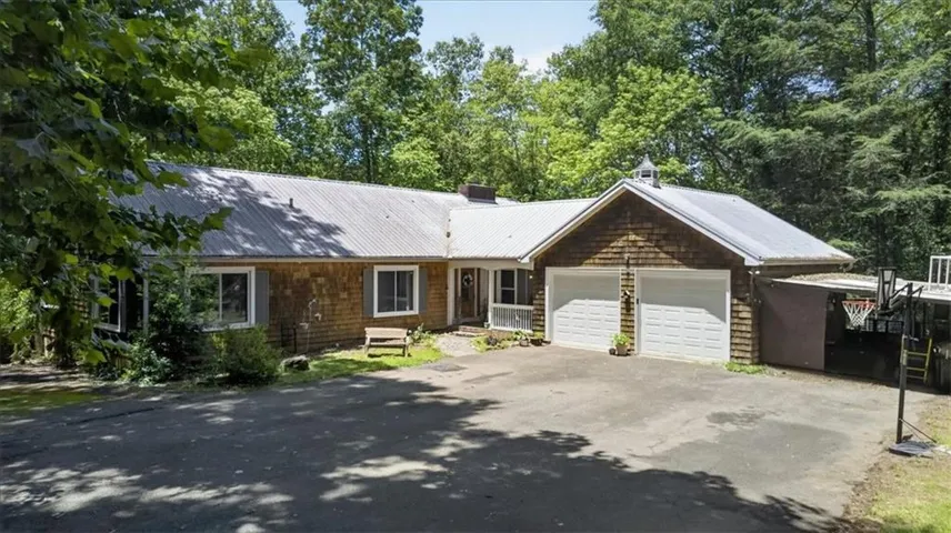 Shingle siding exterior with a metal roof, attached two-car garage, and a paved driveway