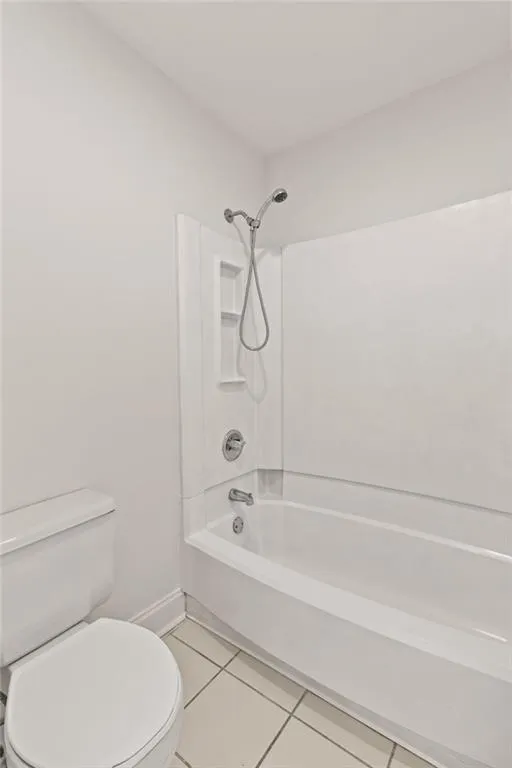 Bathroom with tile patterned flooring, shower / tub combination, and toilet