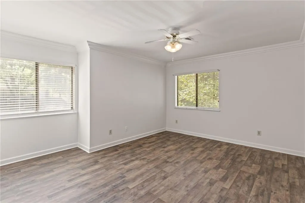 Spare room with crown molding, dark hardwood / wood-style floors, and ceiling fan
